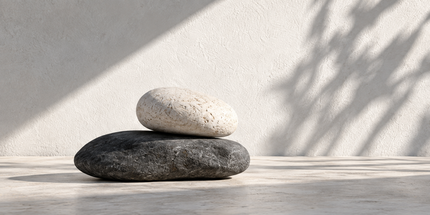 A pale river stone resting on a charcoal stone in soft natural light.